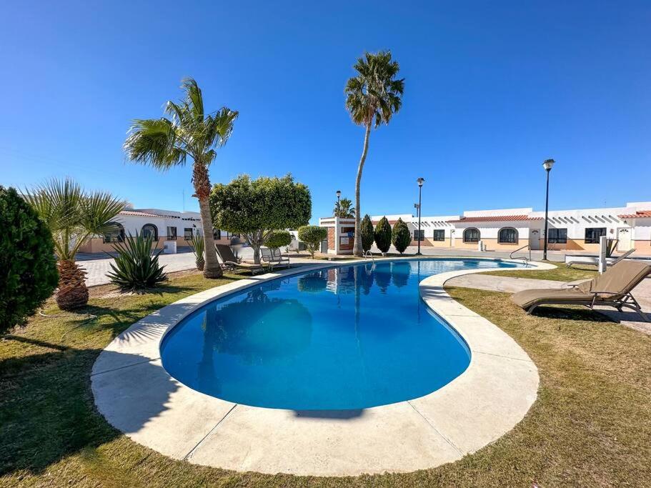 a swimming pool in a resort with palm trees at Mexican Ambience Townhome with Pool #1 in Puerto Peñasco