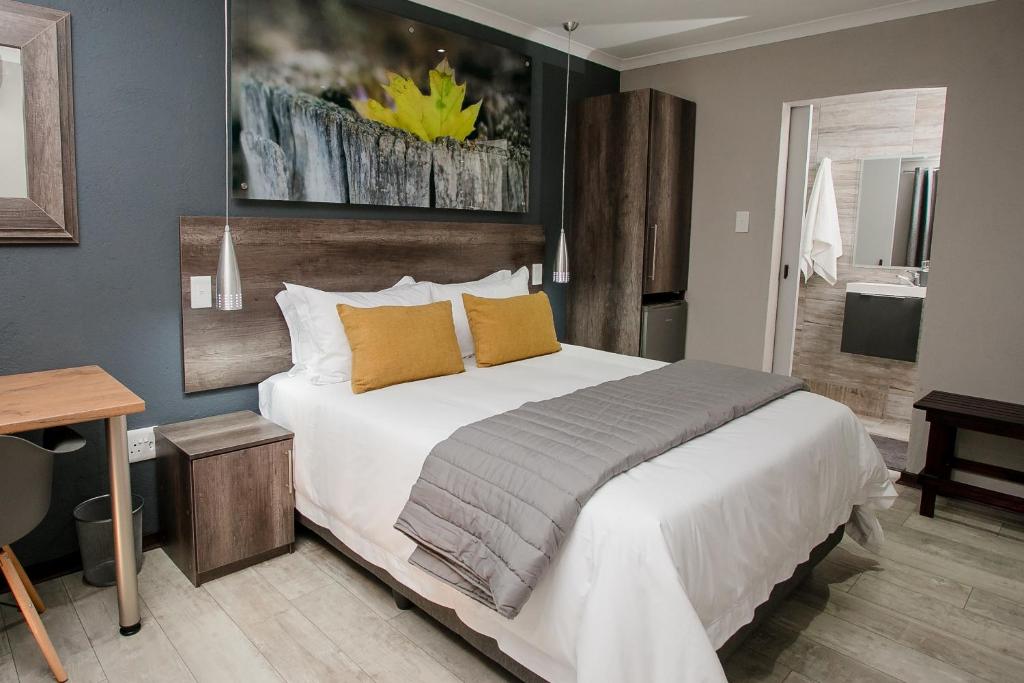 1 dormitorio con 1 cama blanca grande con almohadas amarillas en Vinique Guesthouse, en Nelspruit