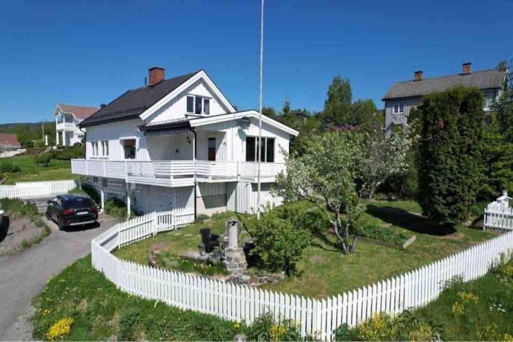 a white house with a white picket fence at Solrikt og sentralt. Ta med både to og firbeinte in Lillehammer