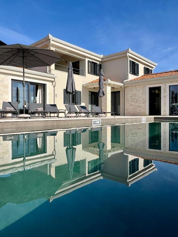 a house with a swimming pool with chairs and an umbrella at Villa Maslinik in Kaštelir