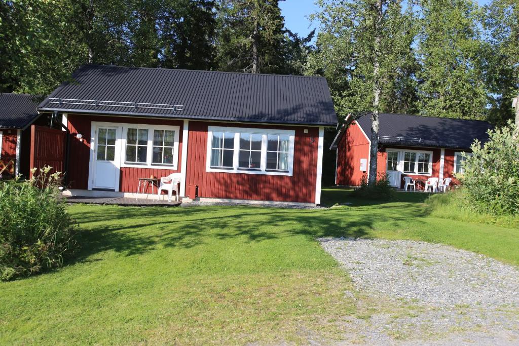 a red house with white windows and a yard at Backs Semesterby in Duved