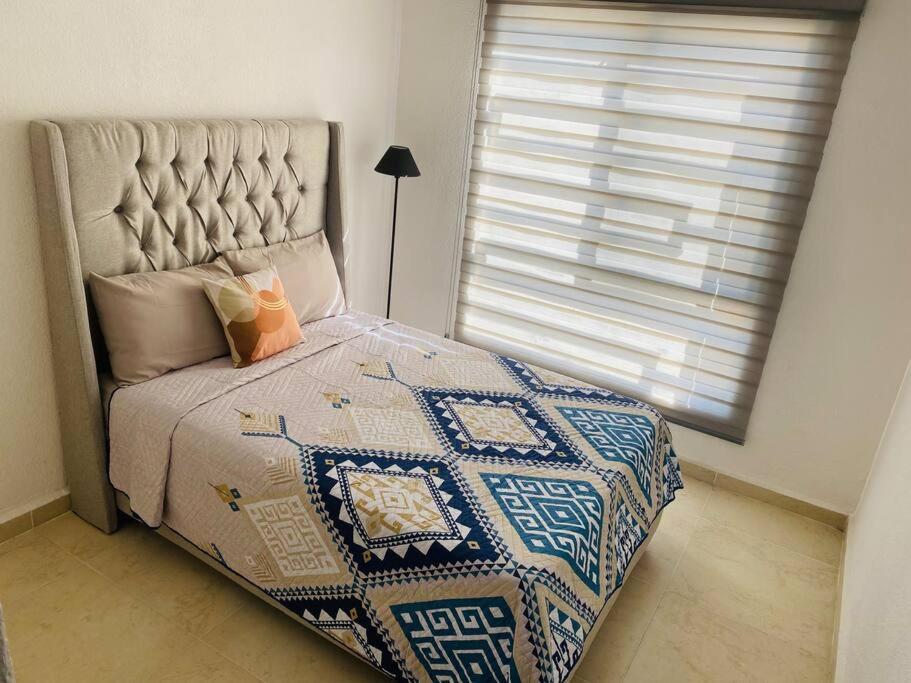 a bedroom with a bed with a quilt and a window at Cómoda Casa cerca de Soledad-Aeropuerto in San Luis Potosí