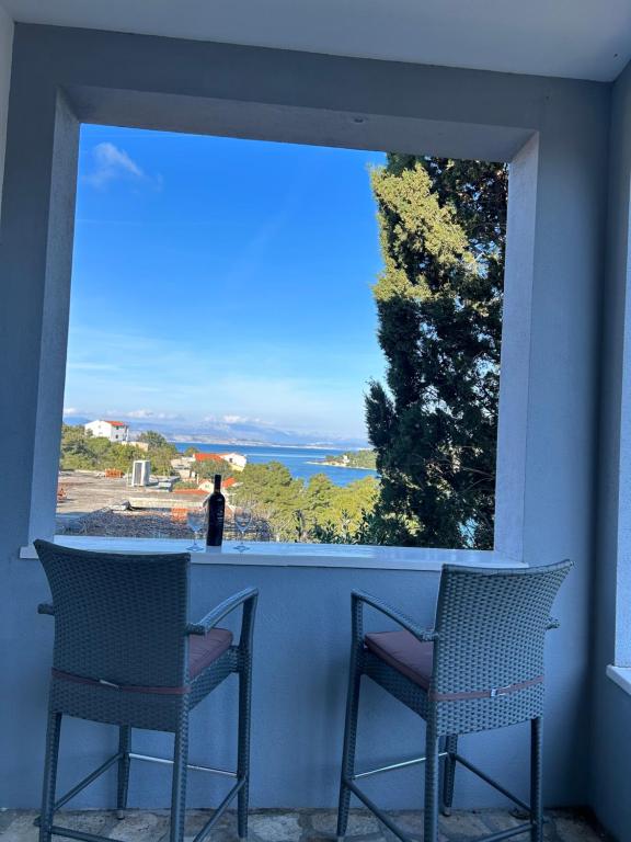 a balcony with two chairs and a view of the ocean at Family house Aldo in Rogač