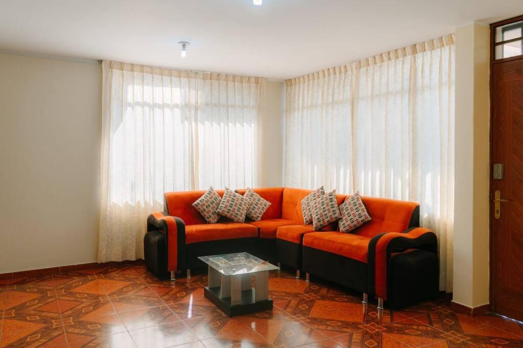 - un canapé orange dans le salon avec une table dans l'établissement MODERNO DEPARTAMENTO CON 4 HABITACIONES, à Huancayo