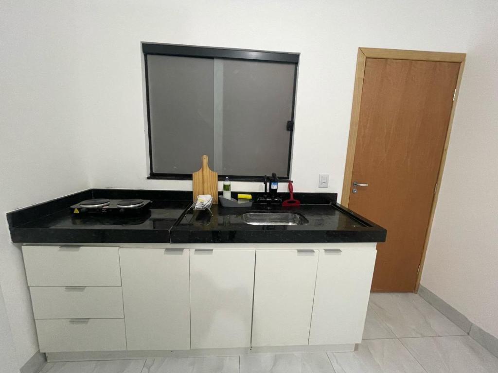 a kitchen counter with a sink and a mirror at Flat Completo Aparecida de Goiânia in Aparecida de Goiania