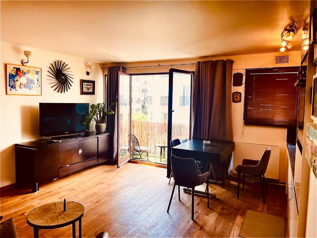 un salon avec une table et une télévision dans l'établissement Jolie 2 pièces avec balcon Paris 15 Eme, à Paris