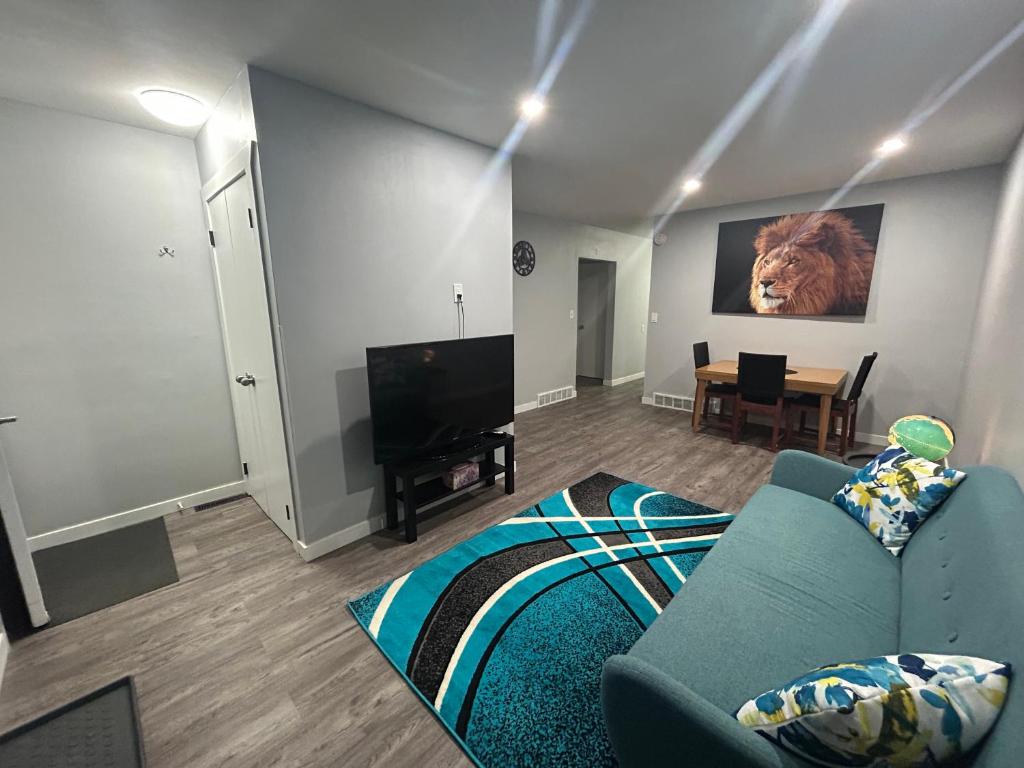 sala de estar con sofá azul y TV en Cute Highland Park Entire Unit A en Calgary