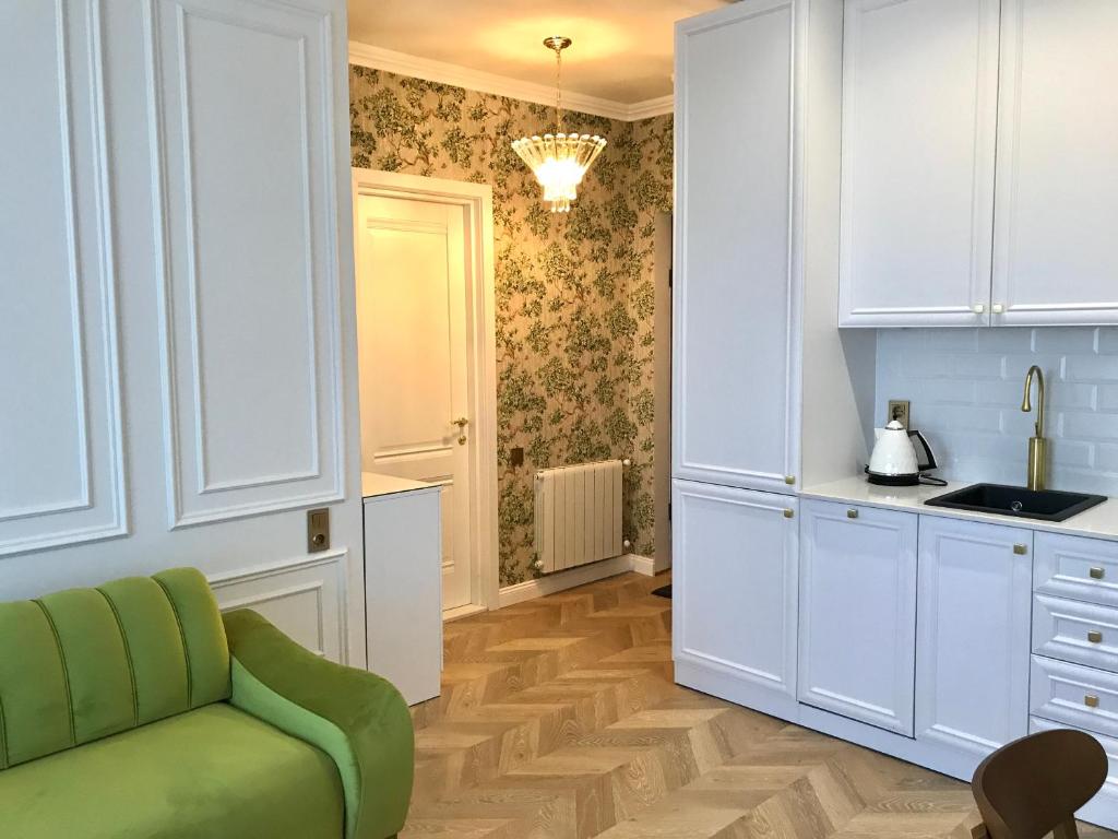 una cucina con armadi bianchi e un divano verde di Brand new 1-bedroom apartment in city centre a Gori