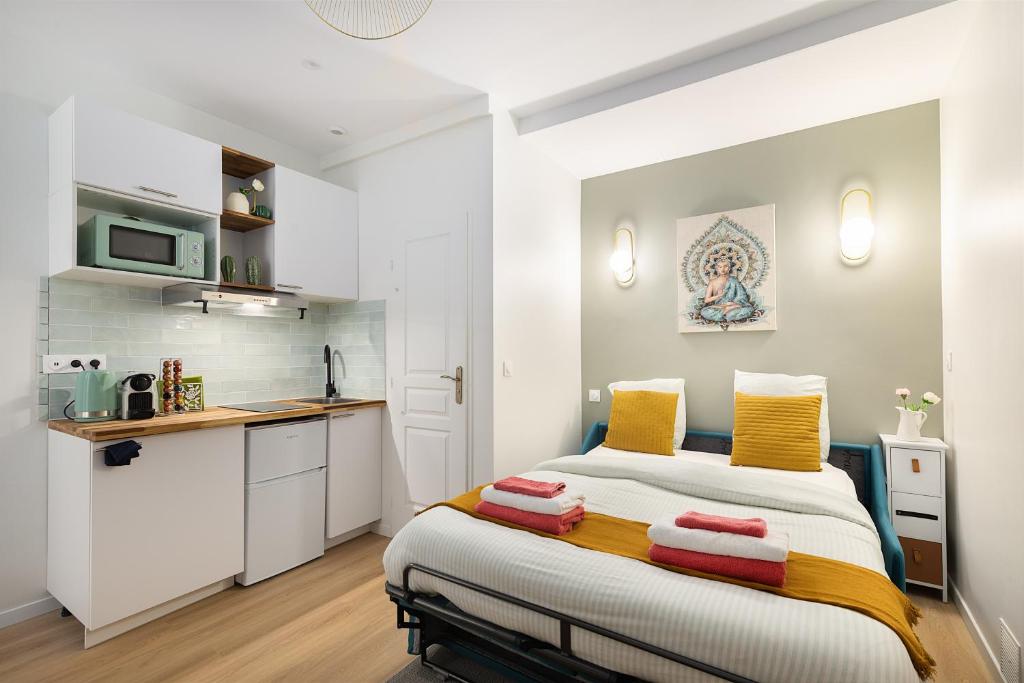 une petite chambre avec un lit et une cuisine dans l'établissement Guestrust - Arc de Triomphe Green, à Paris
