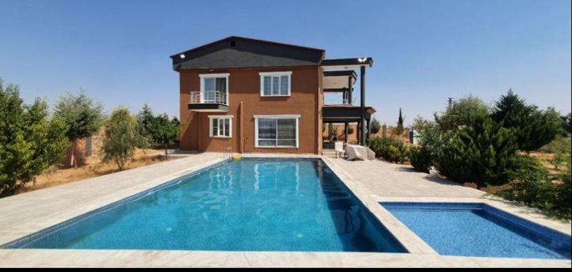 una casa con piscina frente a una casa en Ali Baba Villası en Şahinbey