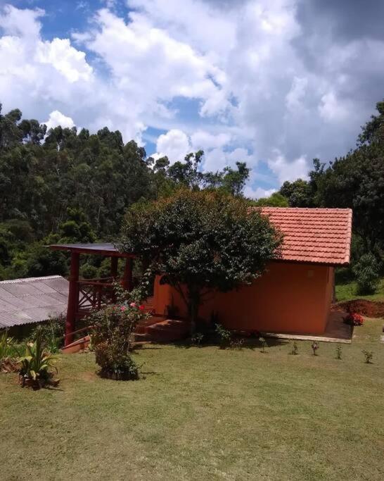 a small house with a red roof and a tree at Chalé Recanto Belo. in São Mateus