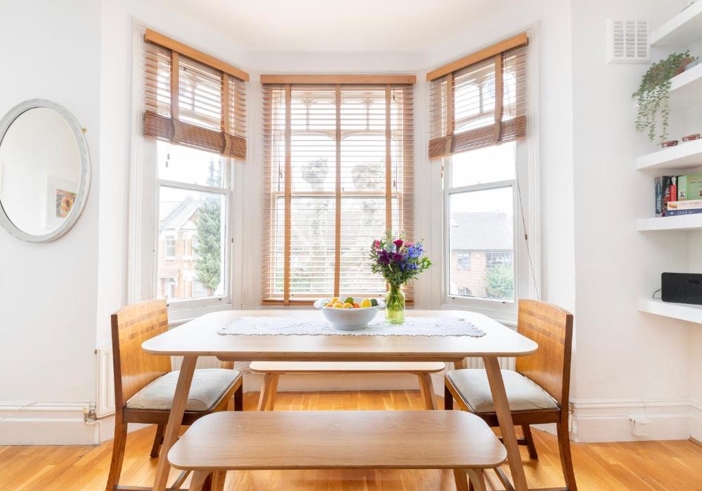 a dining room with a table and chairs and windows at Near Notting Hill 2 bed Spacious apartment Queens Park Nw6 - QPARK in London