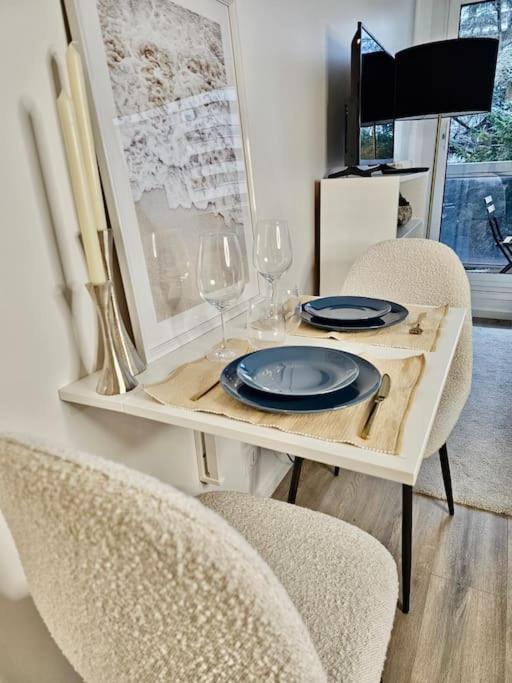 een tafel met borden en wijnglazen erop bij Superbe suite moderne avec balcon et piscine in Boulogne-Billancourt