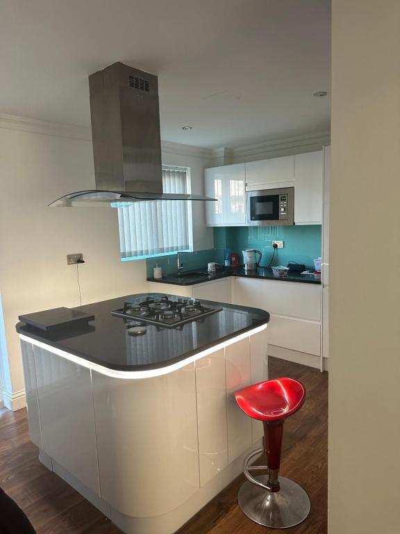 a kitchen with a stove and a red stool at Single Room In A Cosy House In Pitsea in Pitsea