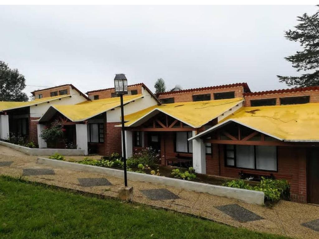 a row of houses with yellow roofs at Hotel y Cabañas Rio Mayo in Chachagüí