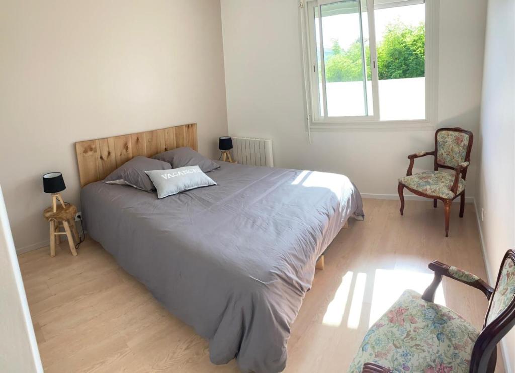 ein Schlafzimmer mit einem Bett, einem Stuhl und einem Fenster in der Unterkunft Maison landaise, 4 chambres avec jardin, classé 3 étoiles in Biscarrosse