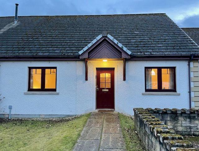 a white house with a red door and windows at Taigh Munro in Aviemore