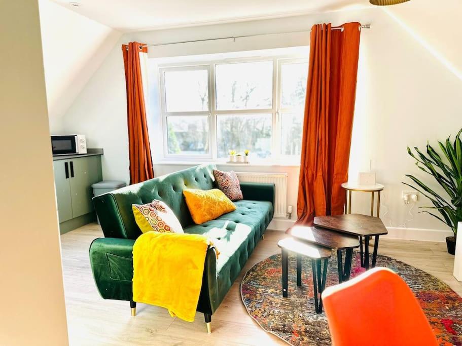 a living room with a green couch and orange curtains at Cosy Dover Flats, Castle view in Kent