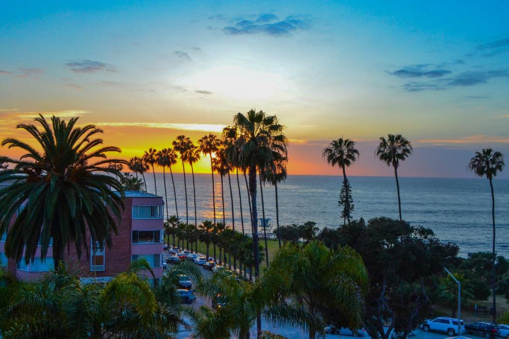 a sunset over the ocean with palm trees and a building at La Valencia Hotel in San Diego