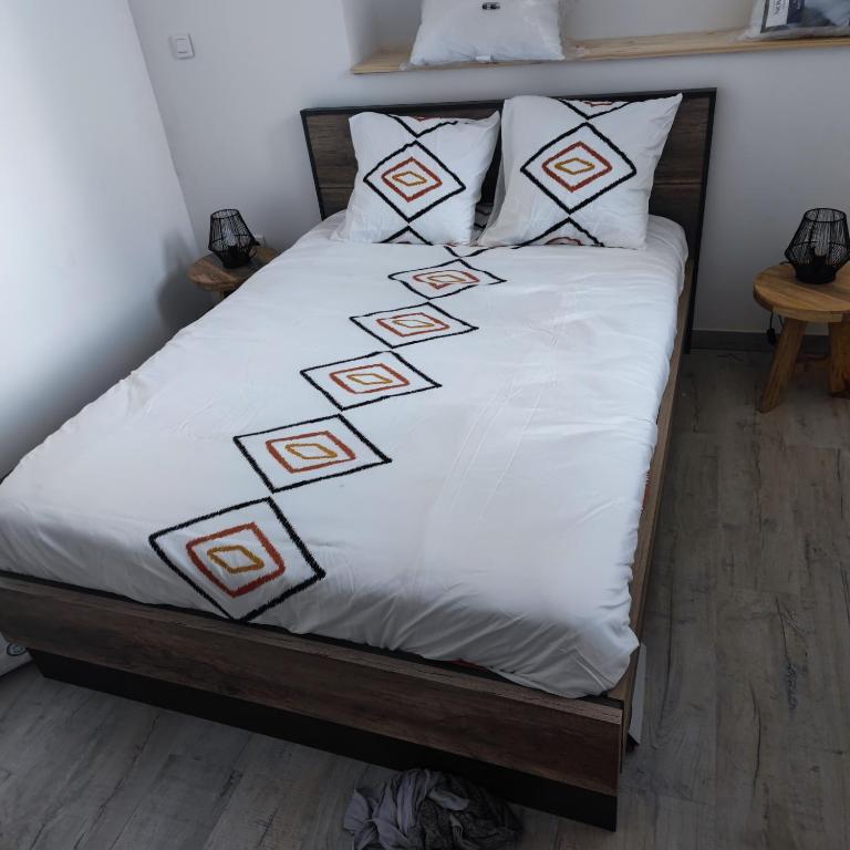 - un lit avec des draps et des oreillers blancs dans l'établissement Appartement centre Merville, à Merville