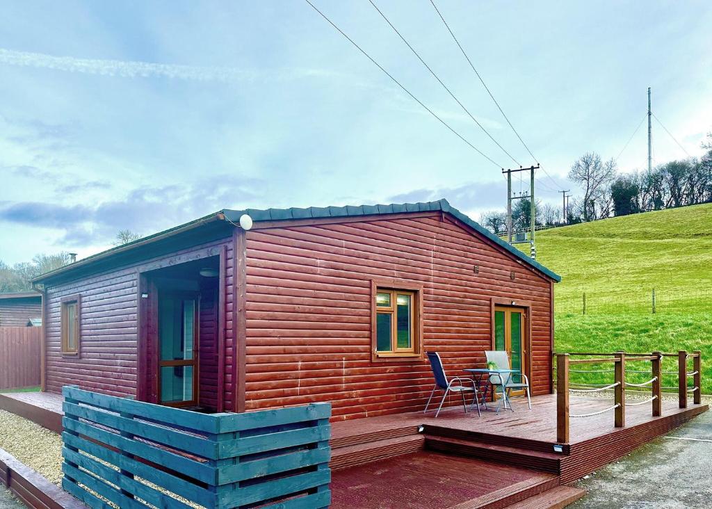 a small wooden cabin with a table on a deck at Pant Wilkin Lodges And Equestrian Centre in Cowbridge