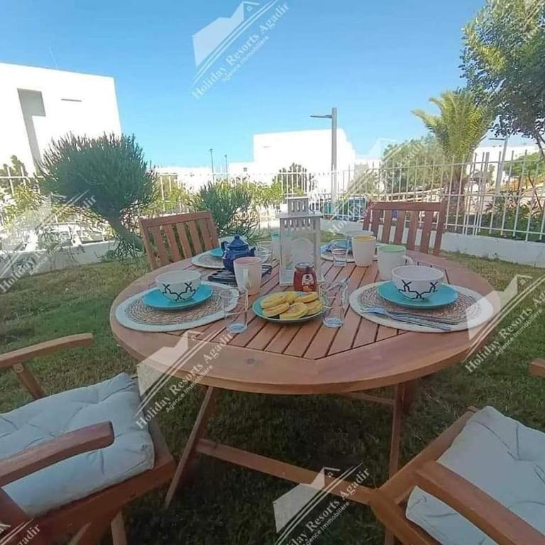een houten tafel met borden eten erop bij Studio Taghazout Bay avec grand jardin in Taghazout