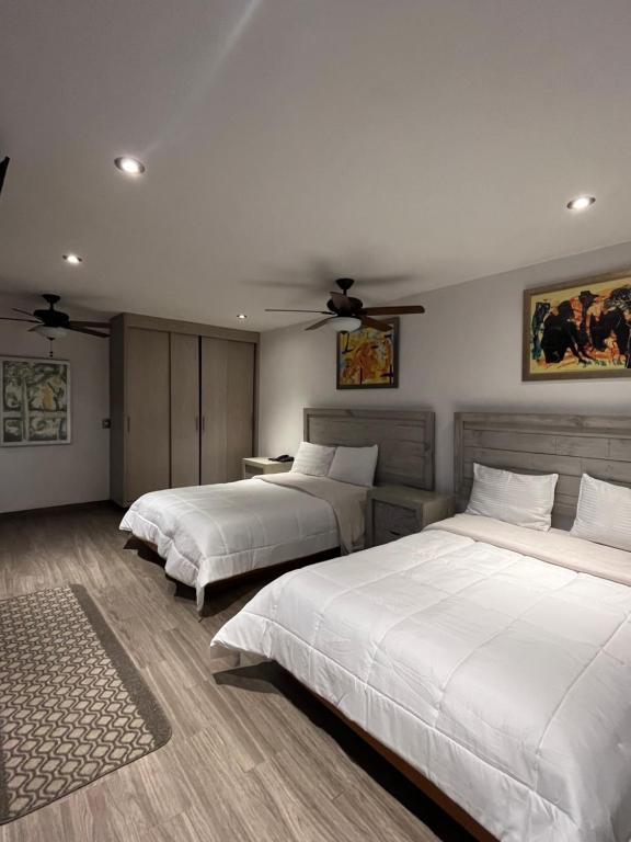 a bedroom with two beds and a ceiling fan at Hotel Casa Carmona in Querétaro