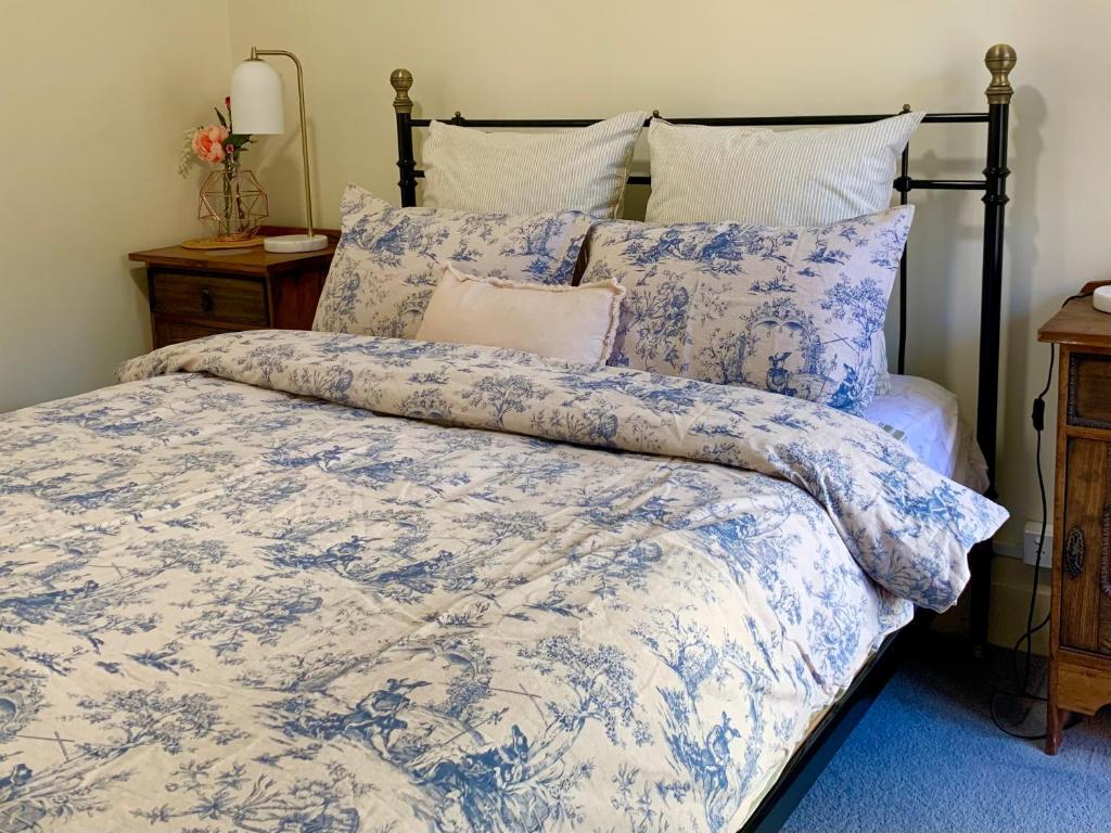 a bed with a blue and white comforter and pillows at La Rouge Cottage in Bendigo