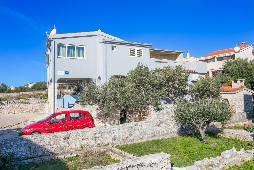 a red car parked in front of a white house at Apartments by the sea Sevid, Trogir - 4287 in Sevid