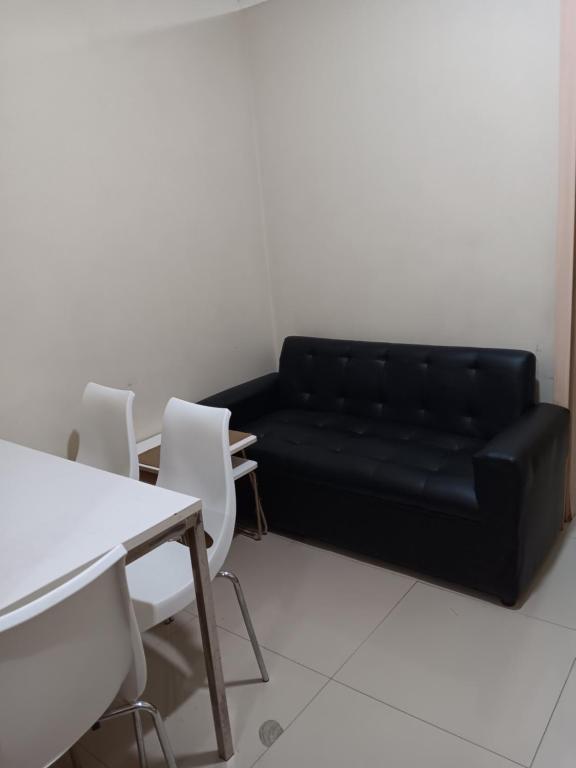 ein schwarzes Sofa in einem Zimmer mit Tisch und Stühlen in der Unterkunft October Homes, Field Residences, Sucat, Parañaque, Airport Express in Manila