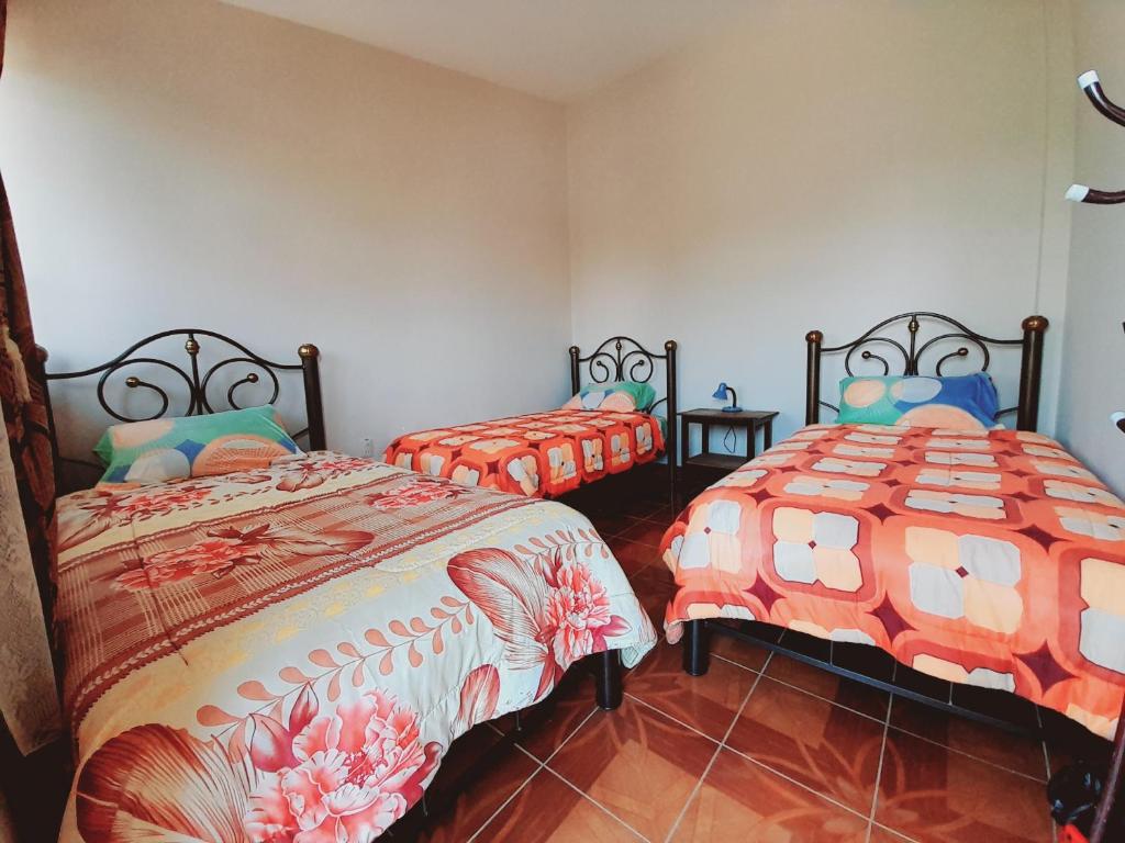 1 dormitorio con 2 camas y edredón de naranja en Hospedaje Matita - Torotoro en Torotoro
