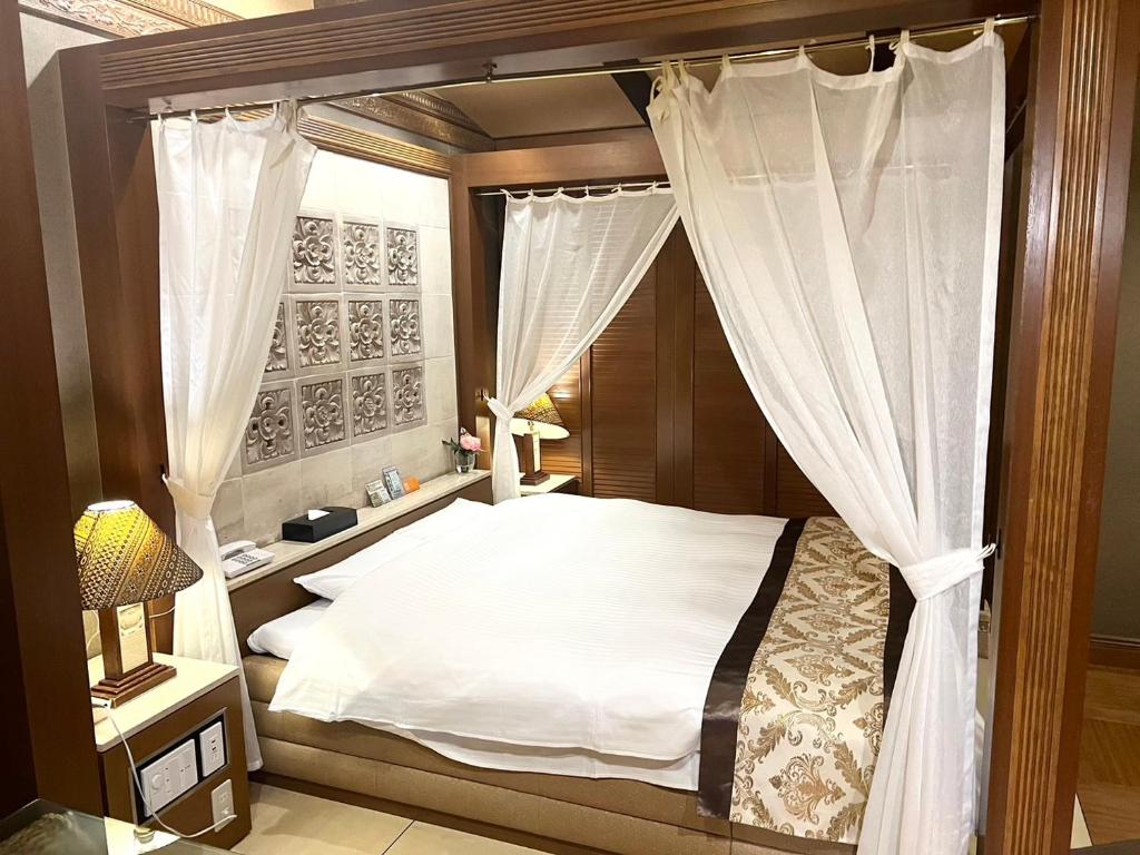 1 dormitorio con cama con dosel y cortinas en Hotel Pareo (Adult Only) en Kobe