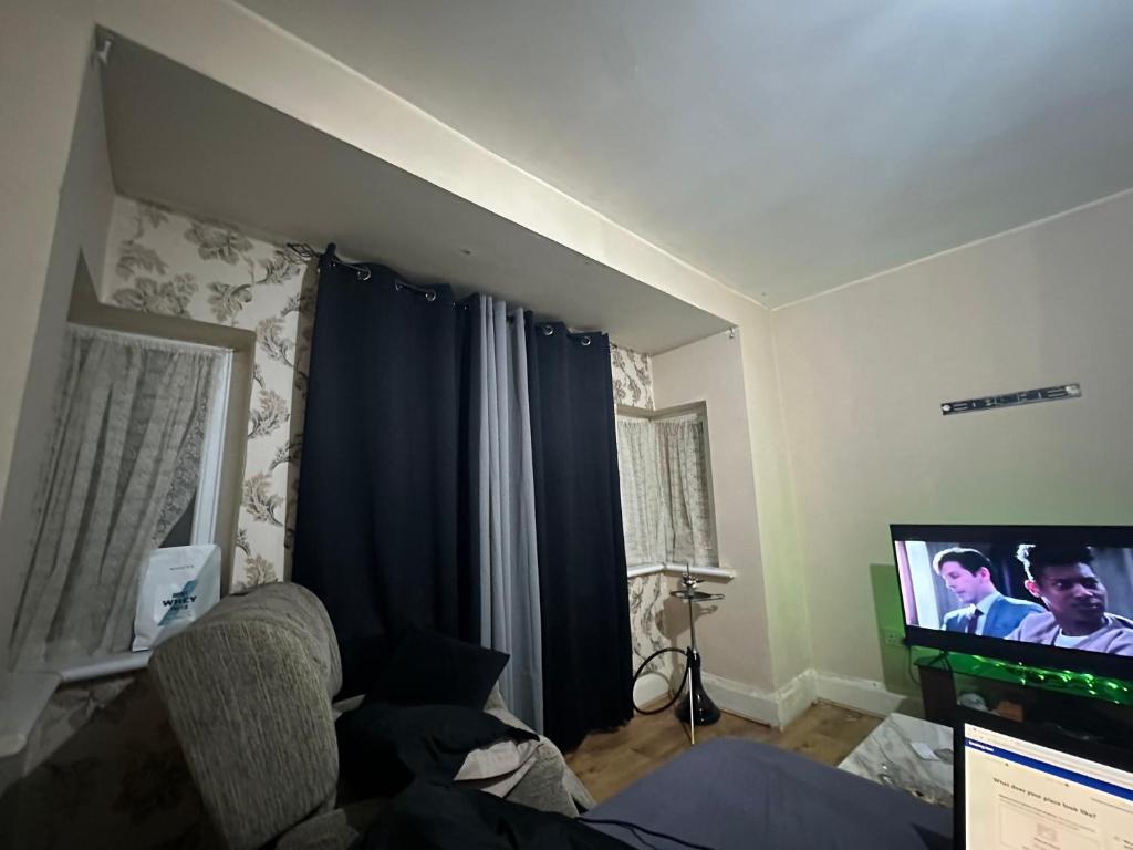 ein Wohnzimmer mit einem Sofa und einem Flachbild-TV in der Unterkunft For your care in Hornchurch