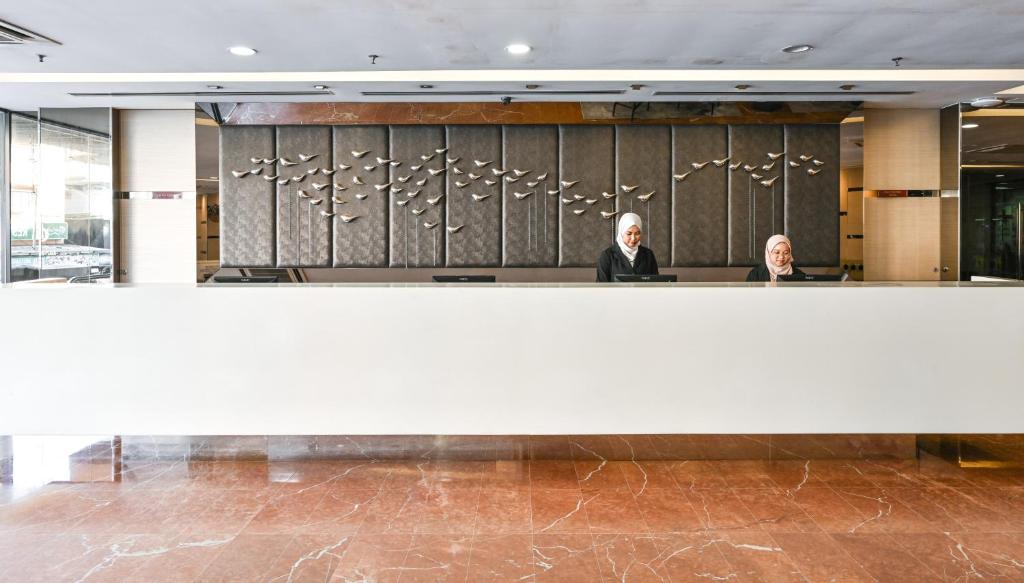 two people sitting at a counter in a lobby at Hotel Pudu Plaza Kuala Lumpur in Kuala Lumpur