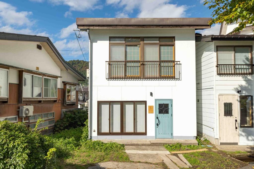 uma casa branca com uma porta azul em Vaisala em Nozawa Onsen