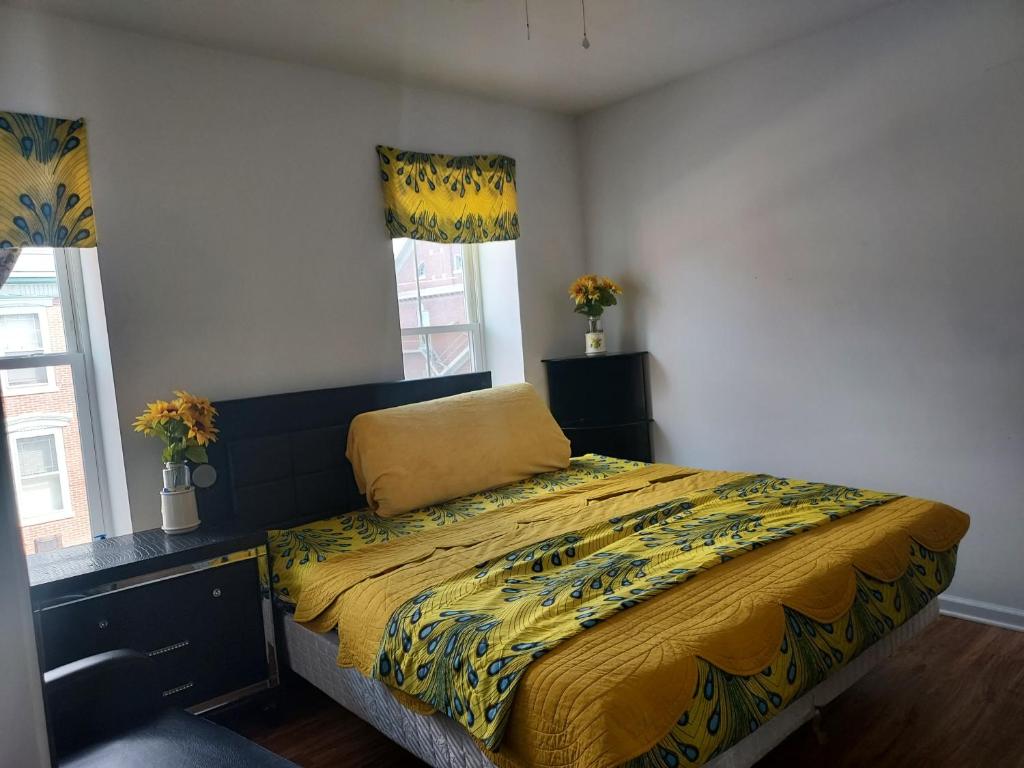 1 dormitorio con 1 cama con edredón amarillo y 2 ventanas en NGU-GI Homess, en Lebanon