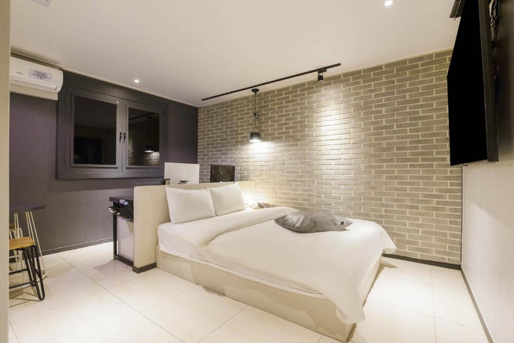 1 dormitorio con cama y pared de ladrillo en Incheon Stay Inn Hotel en Incheon
