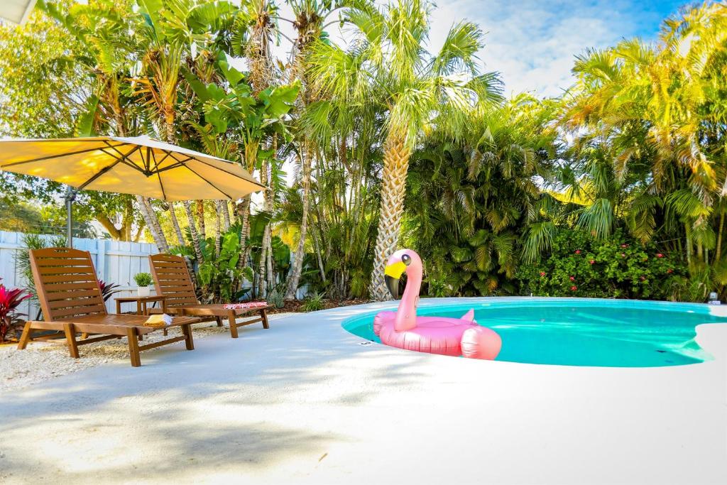 einen rosa Flamingo in einem Pool mit zwei Stühlen und einem Sonnenschirm in der Unterkunft Paradiso Largo - Heated Pool, Mini Golf, Solar Powered Home in Largo