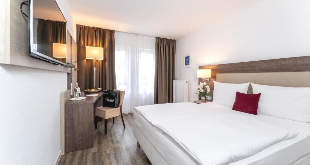 a hotel room with a large bed and a desk at PLAZA INN Karlsruhe Nord in Karlsruhe