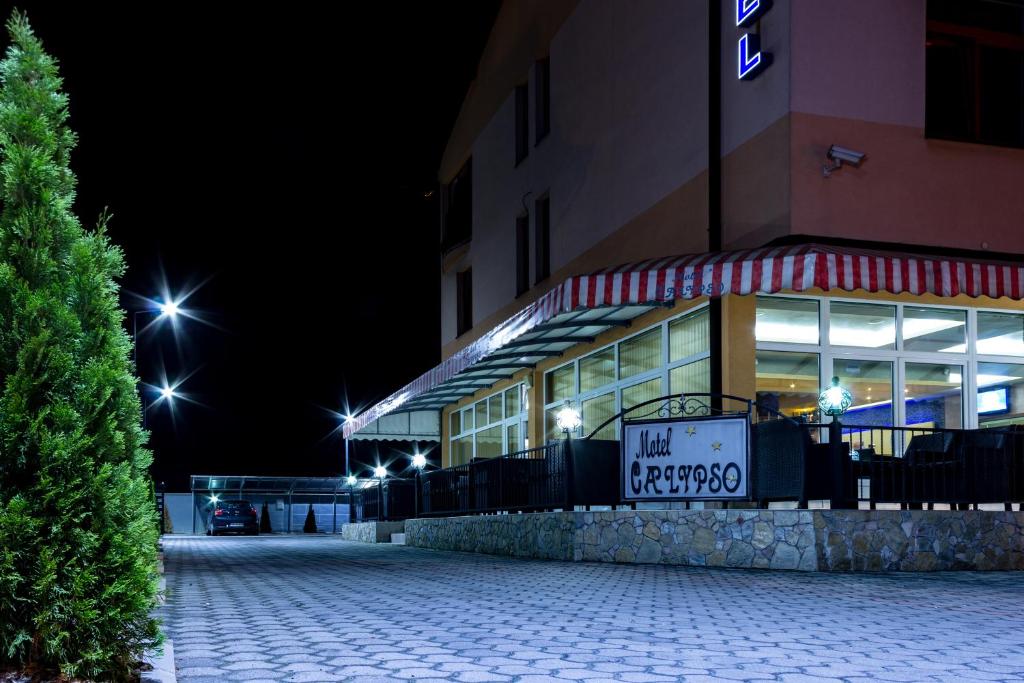 un bâtiment avec un panneau devant lui la nuit dans l'établissement Motel Calypso Travnik, à Travnik