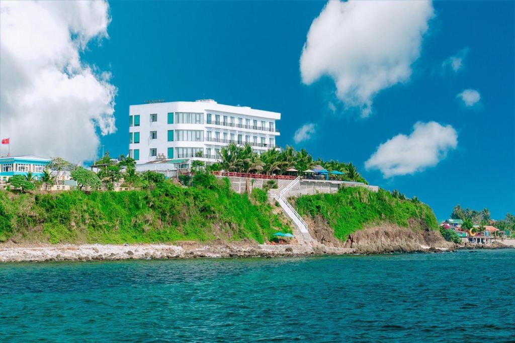 a white building on a hill next to the water at Ly Son Pearl Island Hotel & Resort in Ly Son