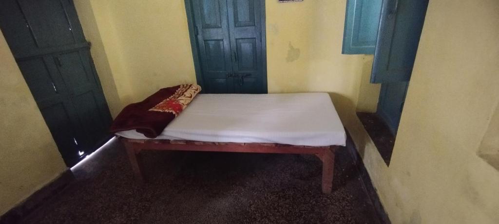 een klein bed in een kamer met 2 deuren bij Sri Viswanatham guest House in Varanasi