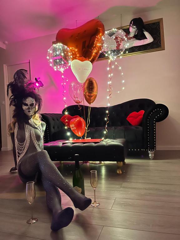 une femme assise sur un canapé avec ballons et verres à vin dans l'établissement Les gîtes coquins, à Amilly