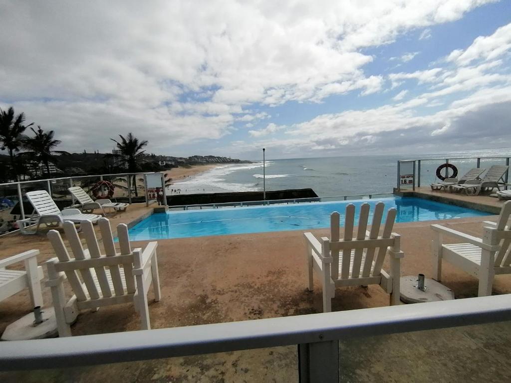 - une vue sur la piscine avec des chaises et l'océan dans l'établissement Sea Breeze, à Margate