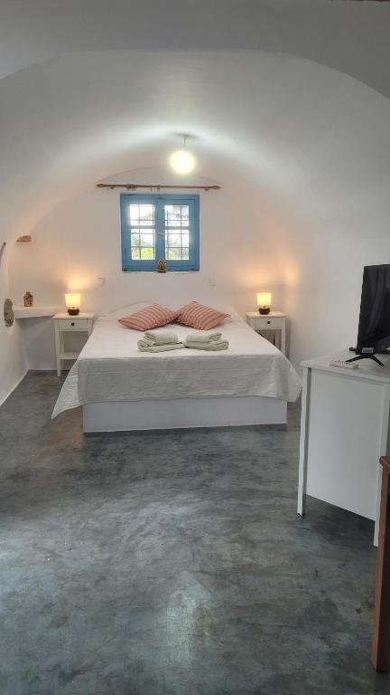 a white bedroom with a bed and a window at Fournos Aroniadika in Kythira