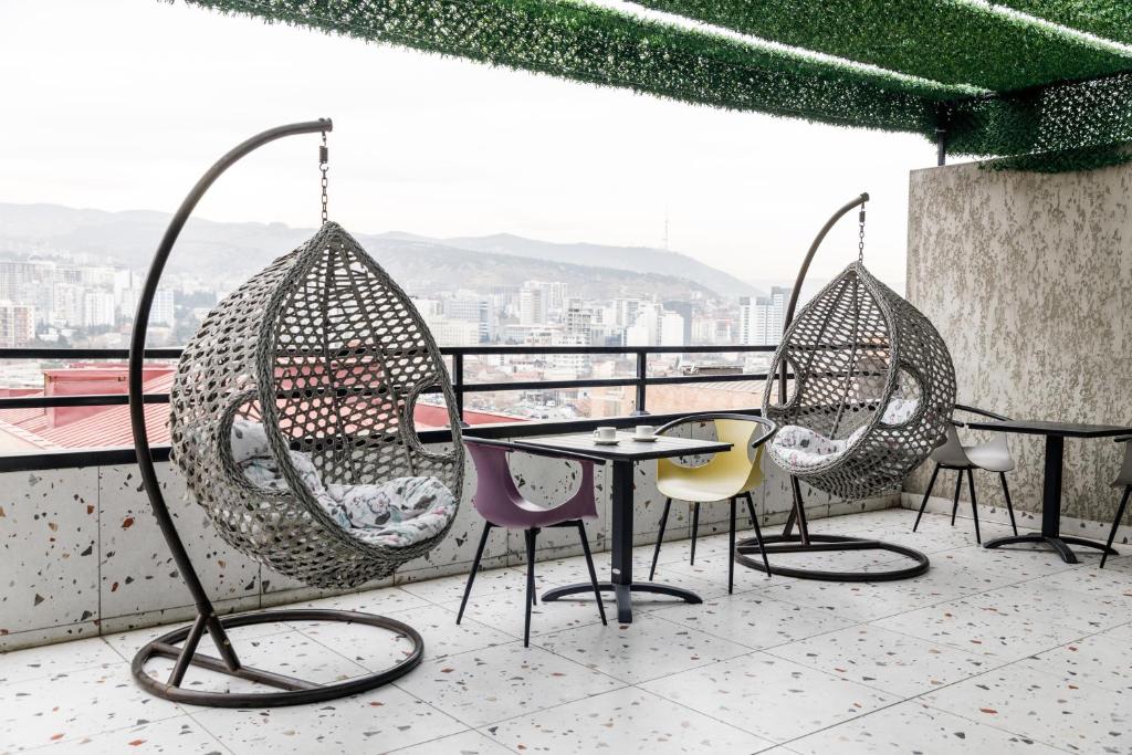 Address Inn في تبليسي: مجموعة من الكراسي والطاولات على الشرفة