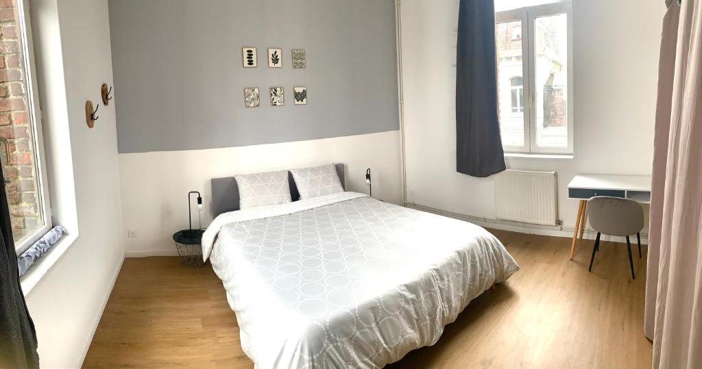 sypialnia z białym łóżkiem i biurkiem w obiekcie La Valencianne w mieście Valenciennes