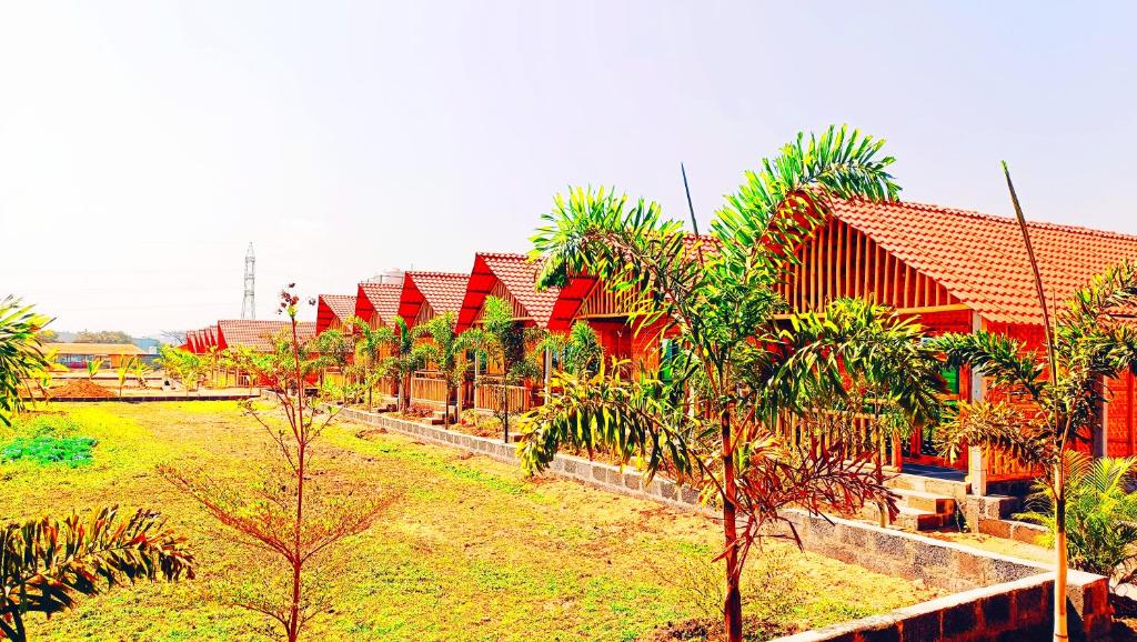 a row of red houses in a field with trees at Osho's Organic Resort Hampi in Hampi