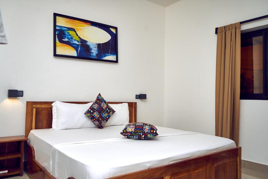 a bedroom with a white bed with two pillows on it at AZURIA HOTEL in Lomé