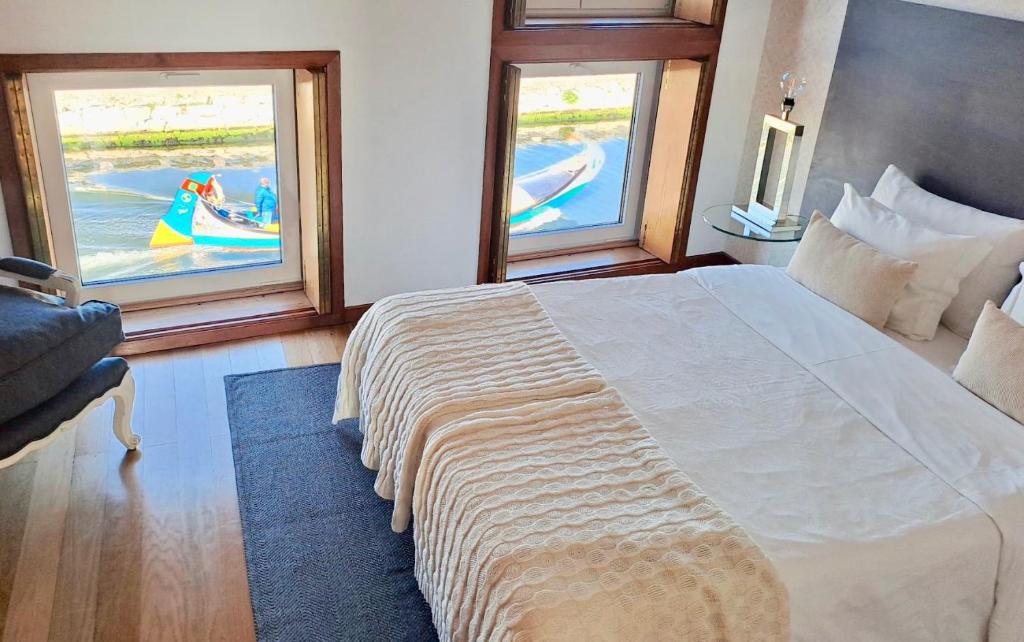 a bedroom with a large bed and two windows at SaberAmar City & Ria & More in Aveiro